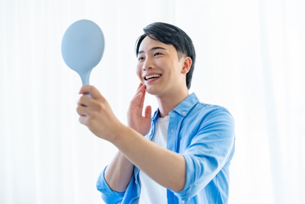 鏡で歯をチェックする男性